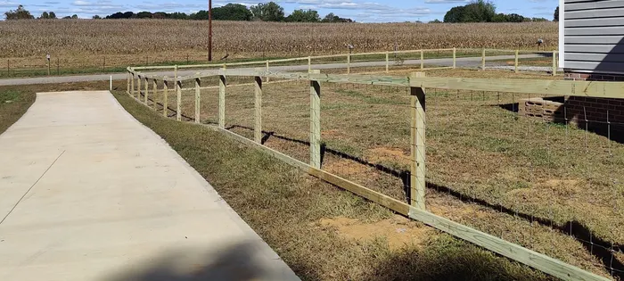 Wood rail fence along a driveway, cornfield beyond