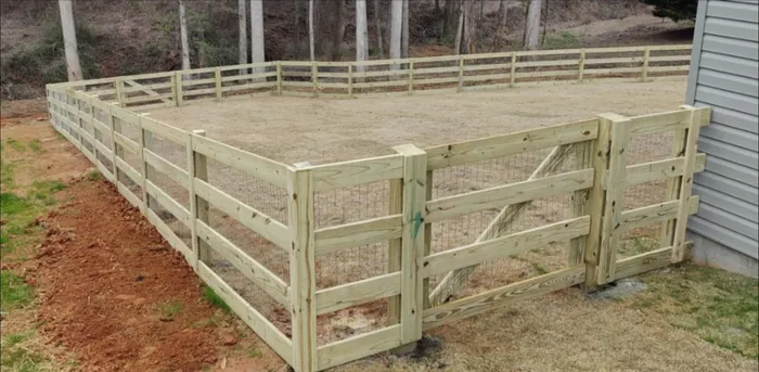 Wood rail and wire fence enclosing a dirt-floor yard