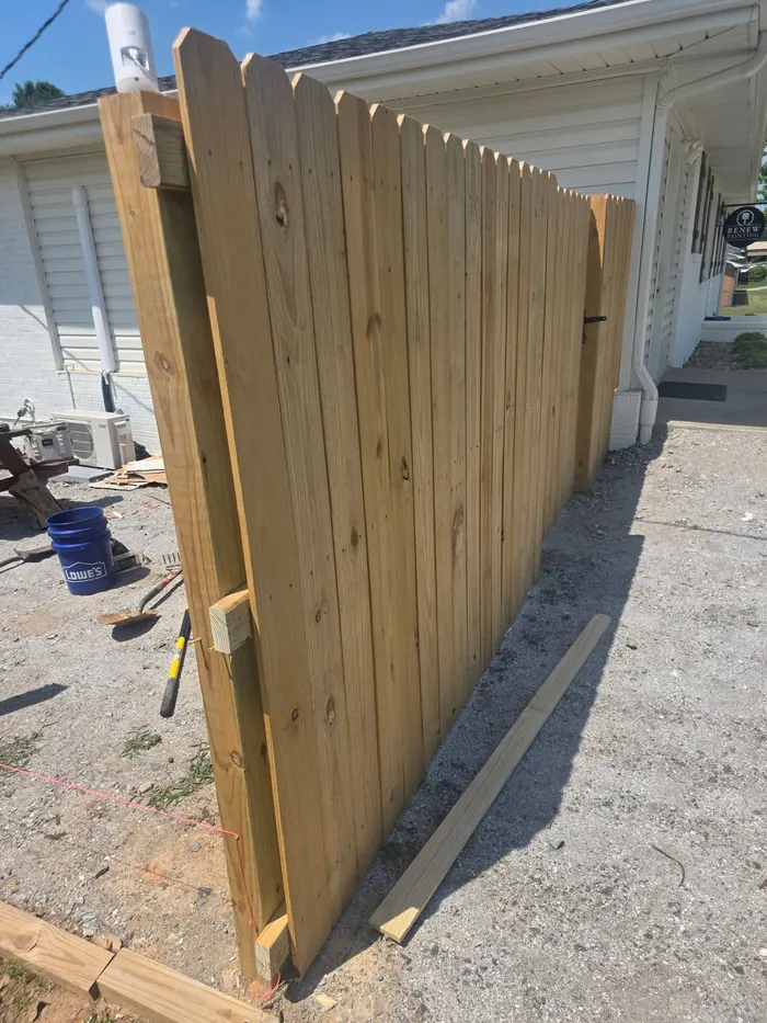 A cedar picket gate under construction, fresh off the sawhorse